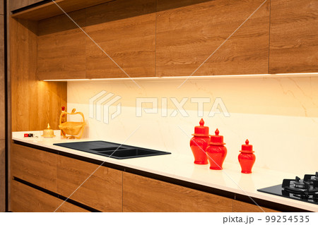 Modern brown wood oak kitchen cabinet equipment, granite black sink and glass gas stove in a home Modern brown wood oak kitchen cabinet equipment, granite black sink and glass gas stove in a home 99254535