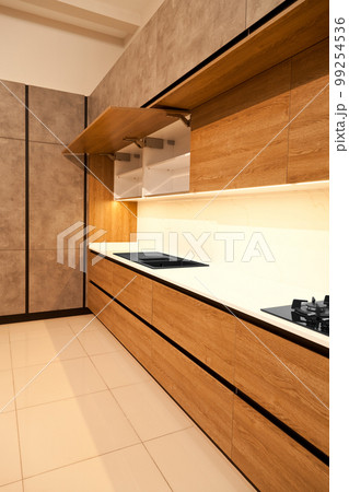 Modern brown wood oak kitchen cabinet equipment, granite black sink and glass gas stove in a home 99254536