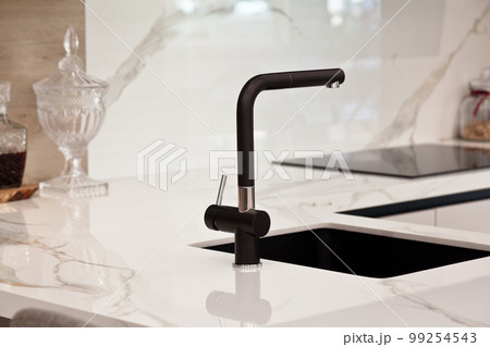 Modern white lacquer and ash tree wood kitchen cabinet and black faucet on white granite countertop 99254543
