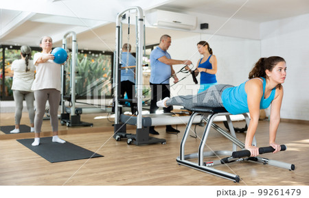 Young girl practicing pilates exercises on combo chair Young girl practicing pilates exercises on combo chair 99261479