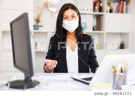 Young businesswoman in medical mask working with laptop Young businesswoman in medical mask working with laptop 99261721