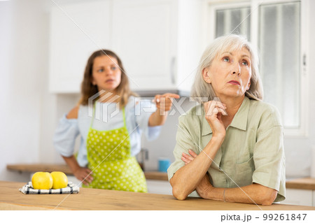 Quarrel of an elderly mother and adult daughter in the kitchen. Adult daughter is unhappy with elderly mother 99261847