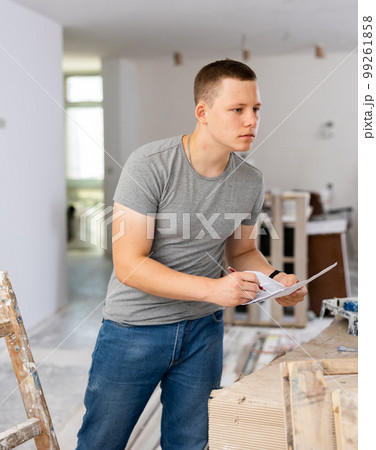 Fifteen-year-old worker fills out paperwork on a construction site indoors 99261858
