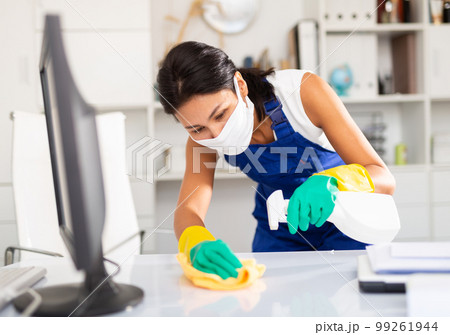 Female cleaner working in protective mask productively on task 99261944