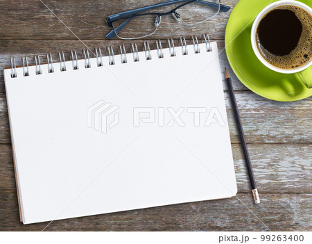 Top view blank notebook,glasses and coffee on wood table background on office desk. 99263400