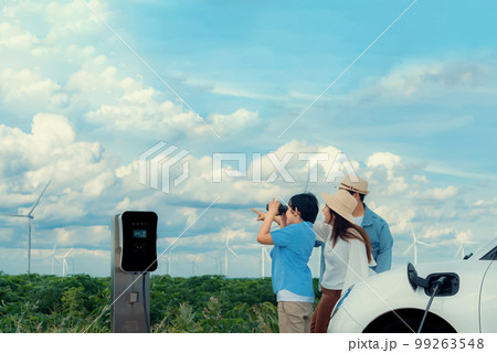 Concept of progressive happy family at wind farm with electric vehicle. 99263548