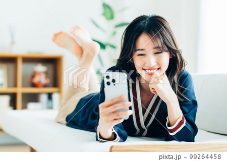 リビングでスマホを使う若い女性 99264458