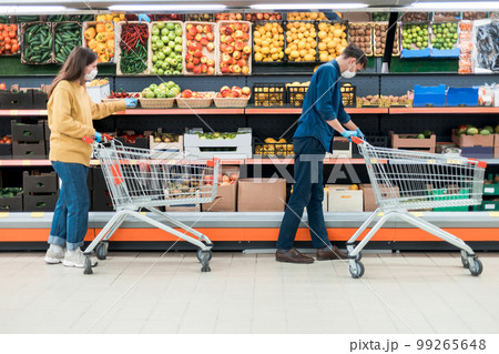 man and a woman with shopping carts in a supermarket during the quarantine period. 99265648