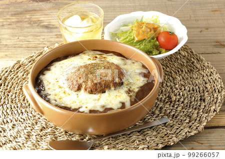 たっぷりのチーズとハンバーグが乗っている焼きカレーとサラダ たっぷりのチーズとハンバーグが乗っている焼きカレーとサラダ 99266057