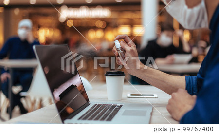 close up . cafe visitor spraying antiseptic on his laptop. close up . cafe visitor spraying antiseptic on his laptop. 99267400