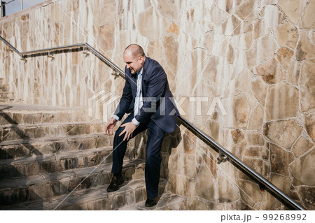 Portrait of a senior professional man in a suit with various problems. A middle-aged businessman with descends the stairs. 99268992