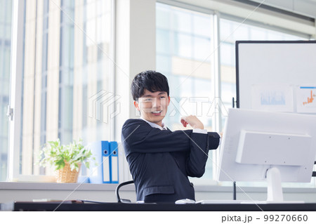 ビジネス　デスクワーク　ストレッチをする若い男性 99270660
