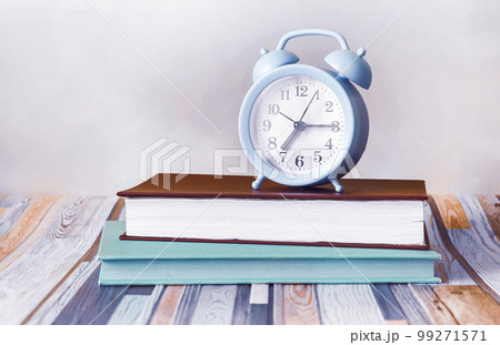 On a light striped background, there are two diaries and a blue alarm clock. On a light striped background, there are two diaries and a blue alarm clock. 99271571