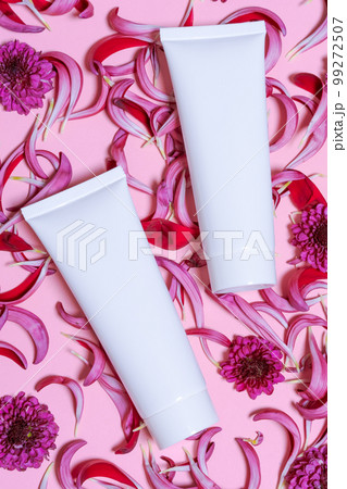 Natural cosmetic products with white bottles and fresh flowers on pink 99272507