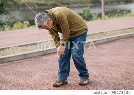 川沿いを歩く膝の痛みを抱えるシニア男性 99272586