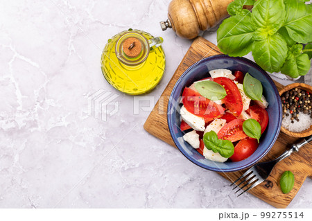 Caprese salad with ripe tomatoes, mozzarella cheese and garden basil Caprese salad with ripe tomatoes, mozzarella cheese and garden basil 99275514