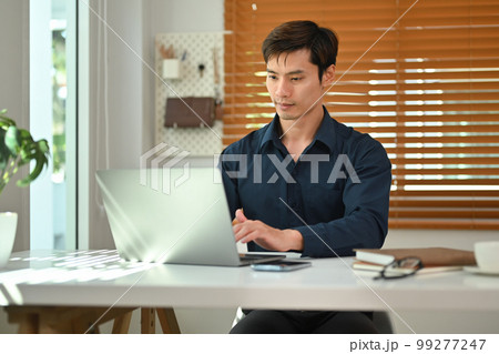 Handsome businessman using laptop computer working at home office. Remote job, technology and lifestyle concept 99277247