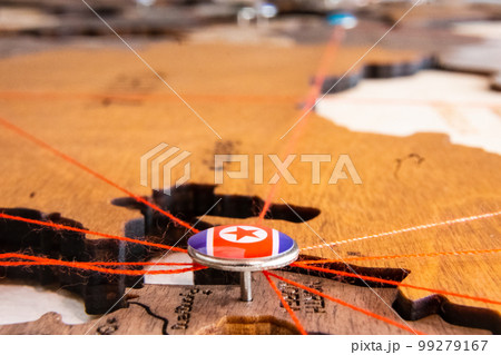 North Korea flag on the pushpin and red threads on the wooden map. Travel or logistic routes. Influence in geopolitics and world economy.  99279167