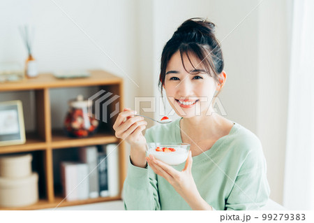 リビングでヨーグルトを食べる若い女性 99279383