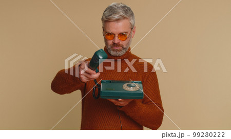 Middle-aged old man talking on wired vintage old-fashioned telephone of 80s advertising call me back 99280222