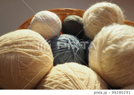 White, beige and blue woolen and acrylic threads wound into a ball or skein. Several skeins of light yarn in a basket. Knitting as a hobby. A clew of thread. White, beige and blue woolen and acrylic threads wound into a ball or skein. Several skeins of light yarn in a basket. Knitting as a hobby. A clew of thread. 99280291