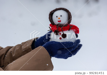 イヤーマフをした雪だるまを持つ人 イヤーマフをした雪だるまを持つ人 99281451
