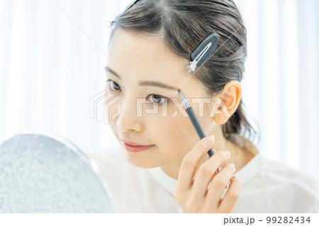 美容　ビューティー　メイク　眉毛を描く若い女性の顔のアップ 99282434