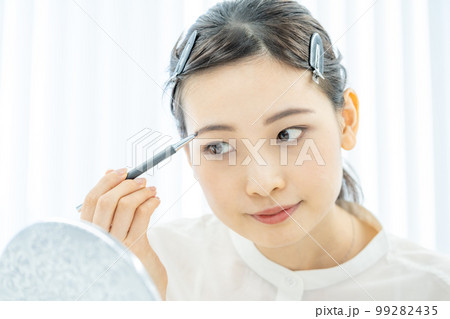 美容　ビューティー　メイク　眉毛を描く若い女性の顔のアップ 99282435