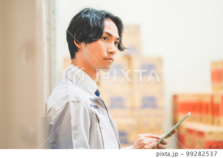 作業服を着て倉庫で在庫管理をする若いビジネスマン 99282537