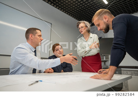 The female boss evaluates the work of subordinates. Designers engineers at a meeting.  99282584