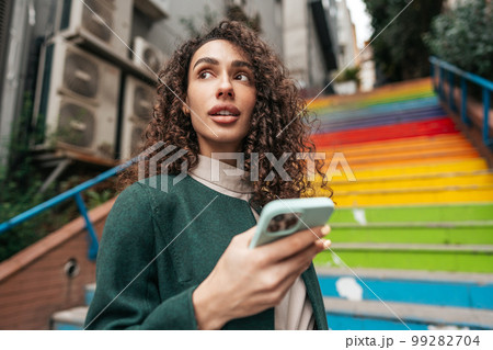 Young attractive woman stands near the rainbow stairs in Istanbul and using a phone Young attractive woman stands near the rainbow stairs in Istanbul and using a phone 99282704