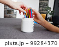 Woman and girl drawing together a coloring with multi-colored pencils, close-up on hand. Home art hobby. 99284370