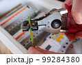 Assembling the electrical panel. An engineer removes insulation from a wire with a stripper against the background of an electrical panel. 99284380