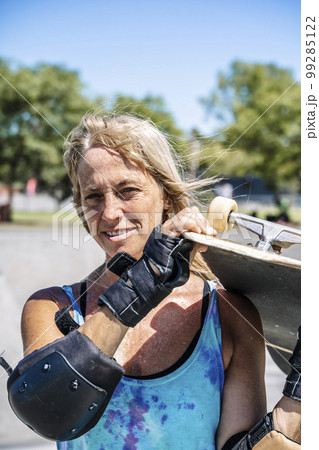 Smiling middle age woman portrait with skateboard in sport lifestyle at summer sunny day. Street urban sporty lifestyle concept. 99285122