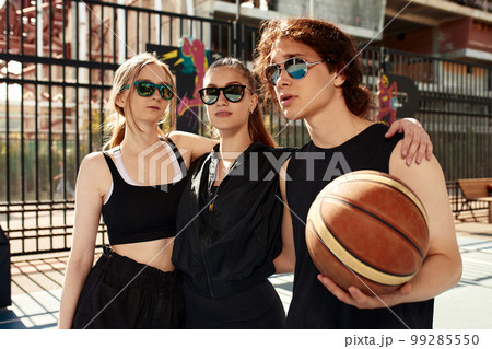 Diversity, guys and girls in sunglasses embracing together on the basketball court, going to play basketball Diversity, guys and girls in sunglasses embracing together on the basketball court, going to play basketball 99285550