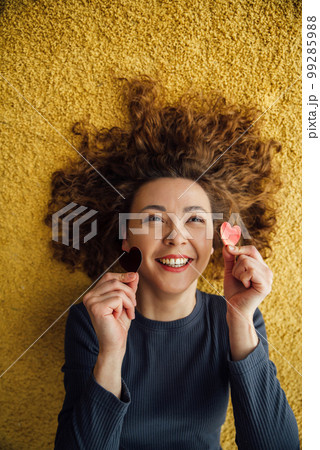 Joyful, laughing Asian woman holds two hearts in her hands Joyful, laughing Asian woman holds two hearts in her hands 99285988