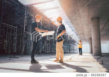 Concept of construction. Engineer, architect and designer working together at the construction site, Foreman or engineer checking the accuracy of the construction work by using blueprints.. 99288367