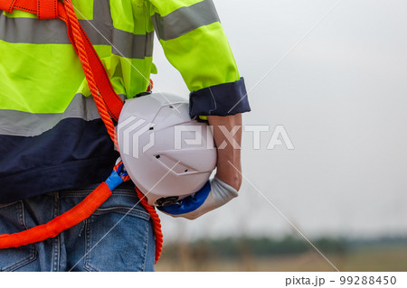 man engineer holding helmet safety wearing uniform standing at wind turbine 99288450