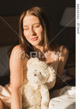 Girl is waking up in morning stretches in bed and sun shines from the window. Happy young woman greets new sunny day Girl is waking up in morning stretches in bed and sun shines from the window. Happy young woman greets new sunny day 99290366
