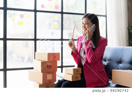 Startup SME small business entrepreneur of freelance Asian woman using a laptop with box Cheerful success happy Asian woman her hand lifts up online marketing packaging and delivery SME idea concept 99290742