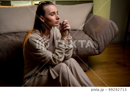 An unhappy woman thinking about problems, sitting by the sofa alone, a disappointed young woman feeling lonely and sad, suffering from a bad relationship, breakup or divorce 99292713