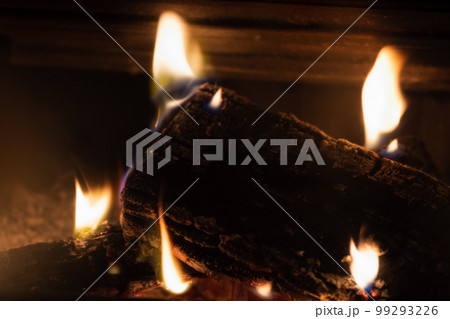 Firewood slowly burns in the fireplace 99293226