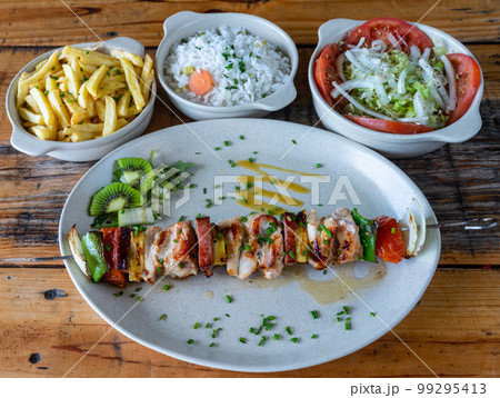 Mixed grilled meat on plate with vegetables salad rice potato cusida. traditional food. Skewer Mixed grilled meat on plate with vegetables salad rice potato cusida. traditional food. Skewer 99295413
