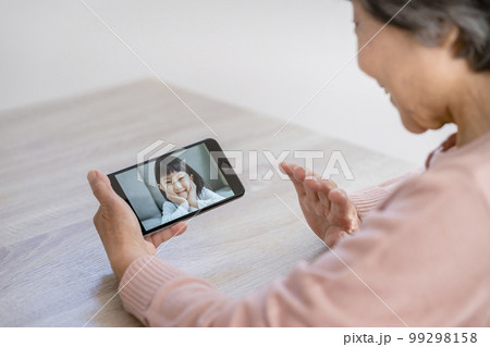 孫とビデオ通話をするシニア女性の手元 孫とビデオ通話をするシニア女性の手元 99298158