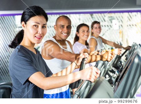 Athletic people running on elliptical trainer in fitness club 99299676