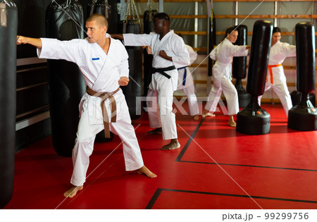 People exercising with punching bags during karate training 99299756