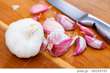 Garlic cloves on wooden table with kitchen knife 99299785