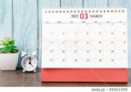 The March 2023 Monthly desk calendar for the organizer to plan 2023 year with alarm clock on wooden table. 99301095
