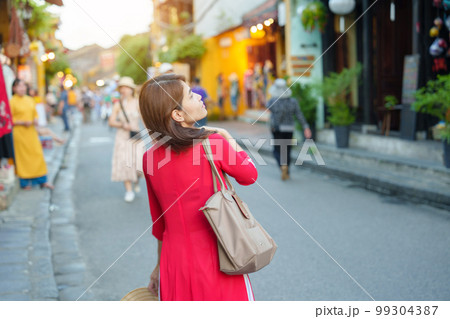 happy woman wearing Ao Dai Vietnamese dress, asian traveler sightseeing at Hoi An ancient town in central Vietnam. landmark and popular for tourist attractions. Vietnam and Southeast travel concept 99304387
