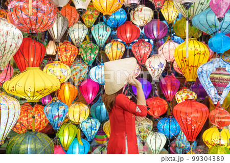 happy woman wearing Ao Dai Vietnamese dress with colorful lanterns, traveler sightseeing at Hoi An ancient town in central Vietnam.landmark for tourist attractions.Vietnam and Southeast travel concept 99304389